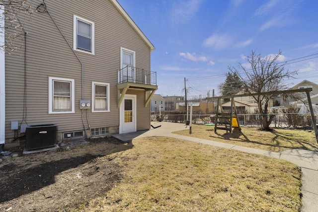 view of yard with a balcony, a playground, central AC, and fence