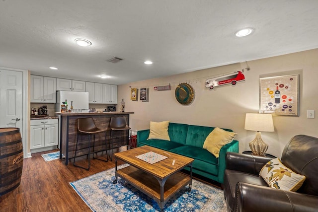 living room with dark wood finished floors, visible vents, and recessed lighting