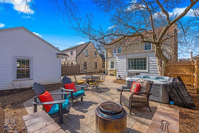 view of patio featuring a fire pit, a hot tub, and fence