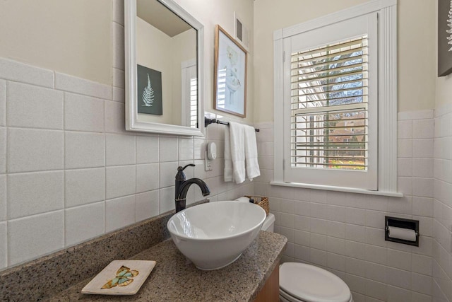 bathroom with visible vents, toilet, tile walls, wainscoting, and vanity