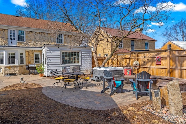 back of property with a patio, fence, and stone siding