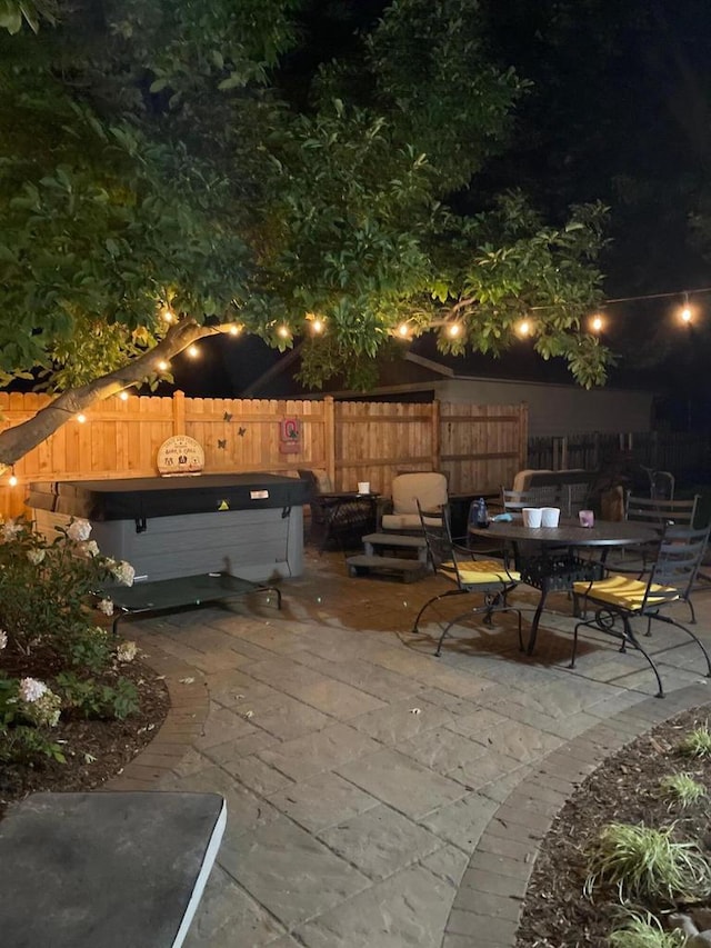 patio at night featuring outdoor dining area and fence