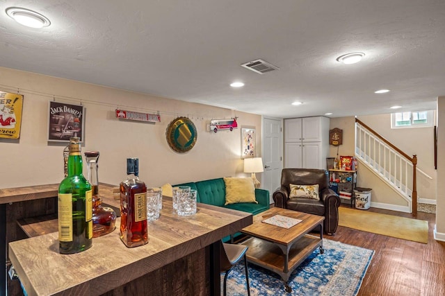 living area featuring wood finished floors, baseboards, visible vents, stairs, and a textured ceiling