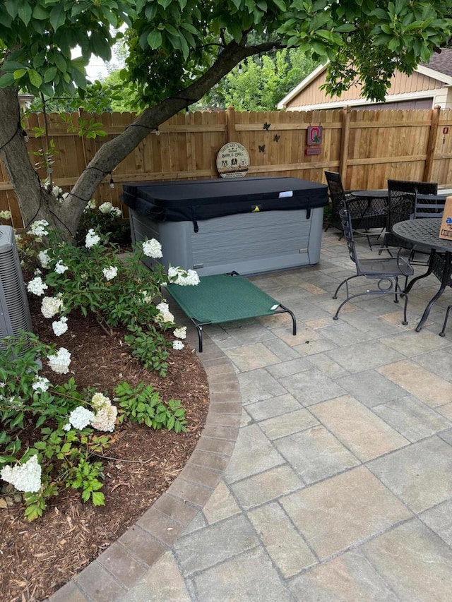 view of patio / terrace featuring fence and a hot tub