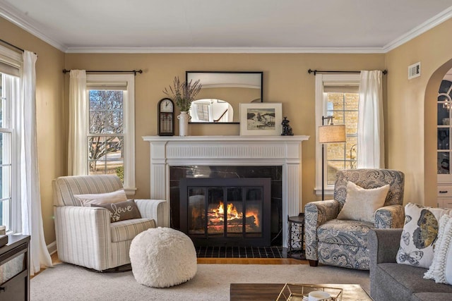 living area with visible vents, arched walkways, plenty of natural light, and a fireplace with flush hearth