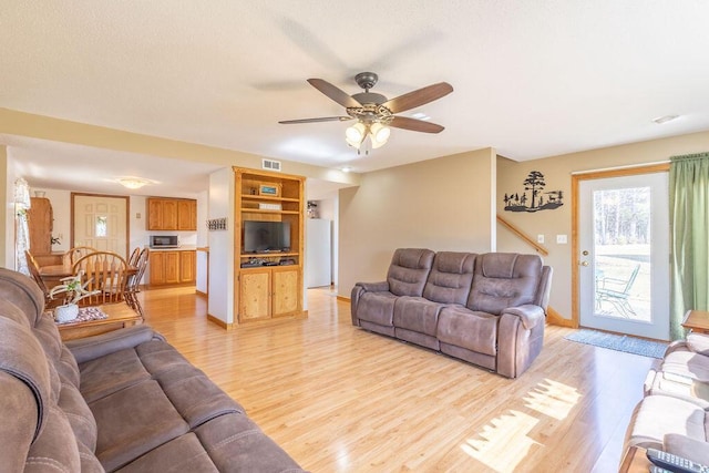 living area with visible vents, baseboards, light wood-type flooring, and a ceiling fan