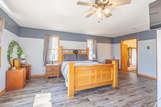 bedroom with baseboards, baseboard heating, attic access, and wood finished floors