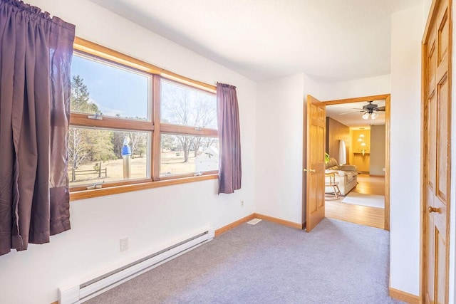 unfurnished bedroom featuring a baseboard heating unit, carpet, and baseboards