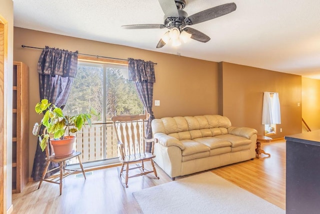 living area featuring a textured ceiling, wood finished floors, and ceiling fan