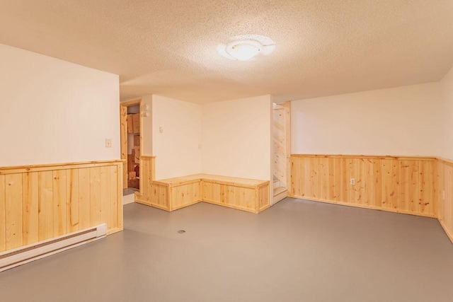 basement with wooden walls, a wainscoted wall, and a textured ceiling