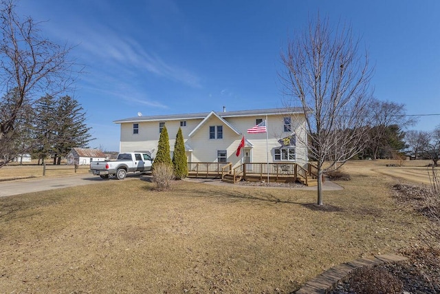 view of front of property with driveway, a wooden deck, and a front yard