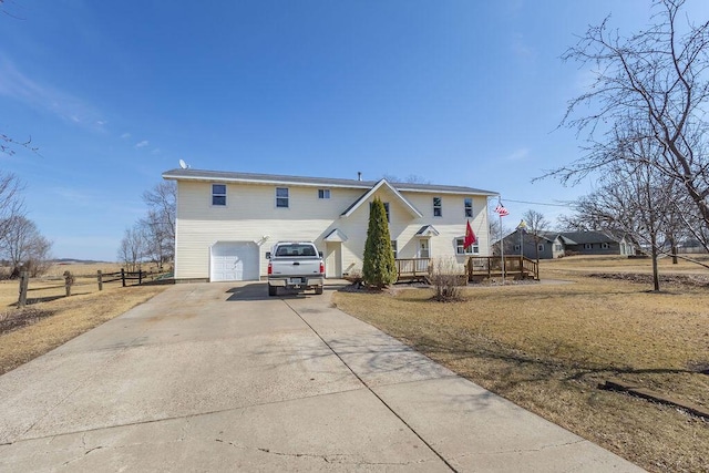 view of front facade with an attached garage, concrete driveway, and fence