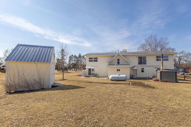 back of house with metal roof, a storage shed, an outdoor structure, and a lawn