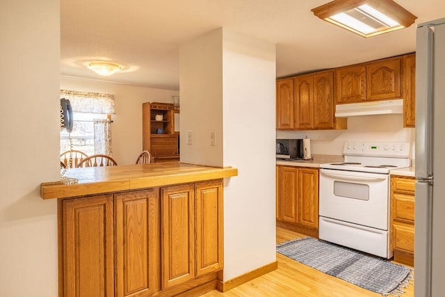 kitchen featuring white range with electric cooktop, under cabinet range hood, light wood-type flooring, light countertops, and brown cabinetry