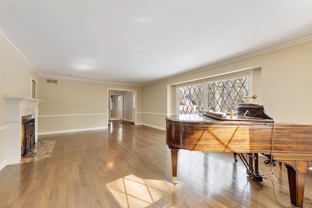 office area with visible vents, crown molding, baseboards, and wood finished floors