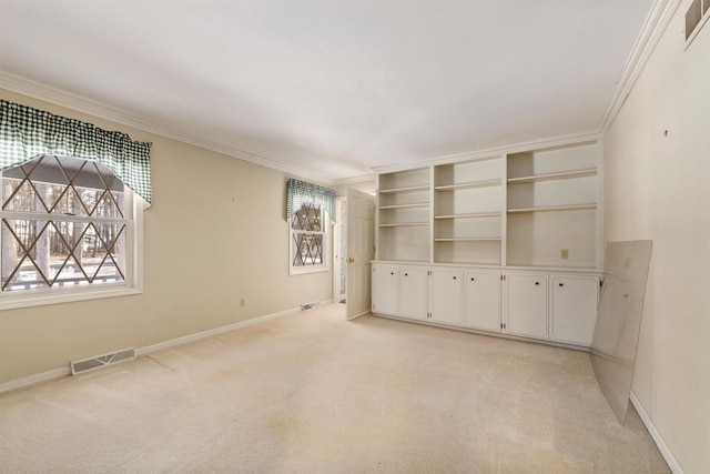 empty room featuring a wealth of natural light, visible vents, and crown molding