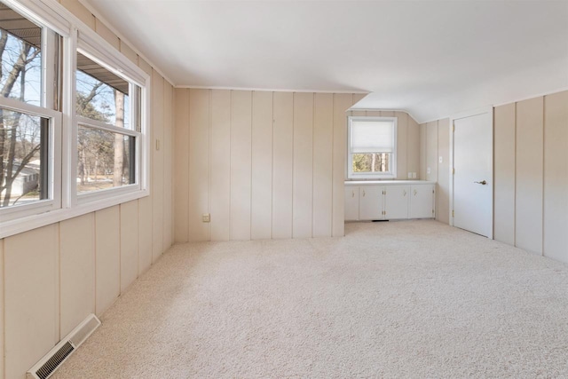 interior space featuring light carpet, visible vents, and vaulted ceiling