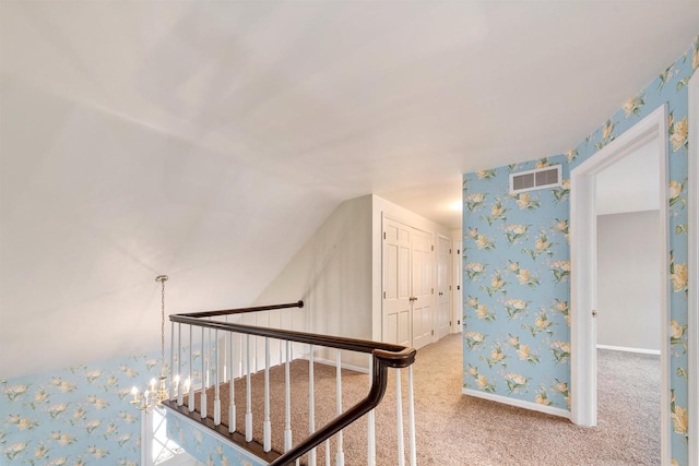 stairway featuring baseboards, visible vents, carpet floors, wallpapered walls, and lofted ceiling