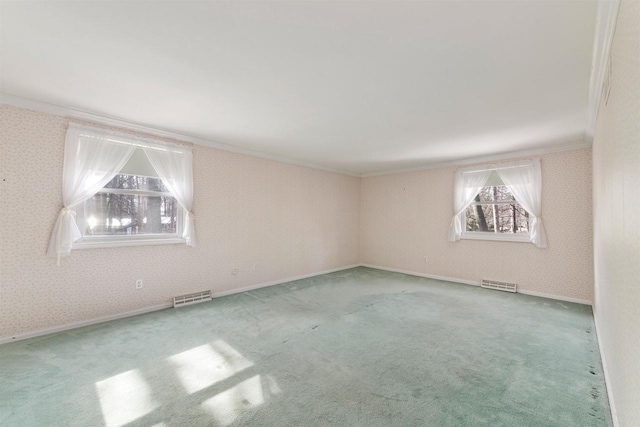 carpeted empty room with visible vents, wallpapered walls, crown molding, and baseboards