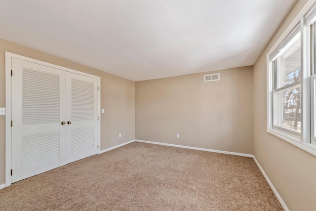 unfurnished room with visible vents, carpet floors, and baseboards