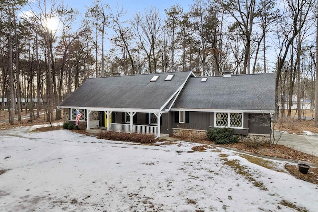 view of front of home featuring stone siding, covered porch, a chimney, and a shingled roof