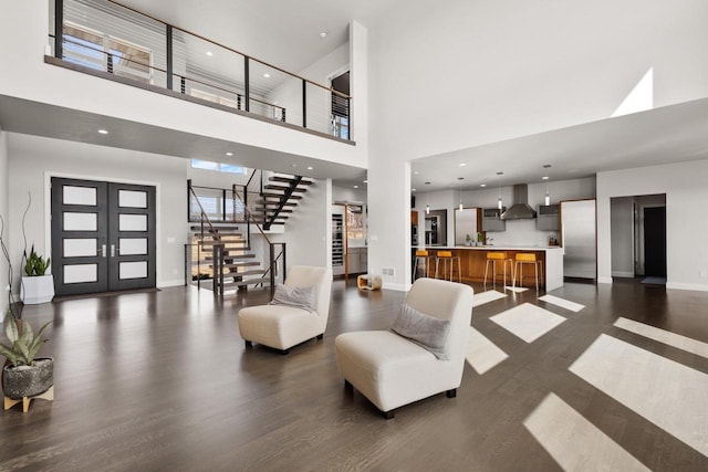 living area with dark wood-type flooring, baseboards, stairs, recessed lighting, and a towering ceiling