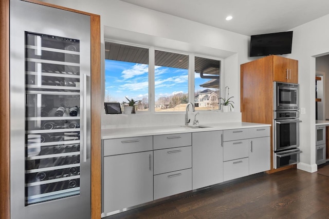 kitchen with a warming drawer, a sink, wine cooler, appliances with stainless steel finishes, and light countertops