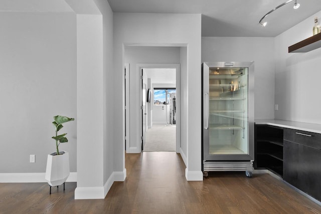 bar featuring dark wood finished floors, built in refrigerator, and baseboards