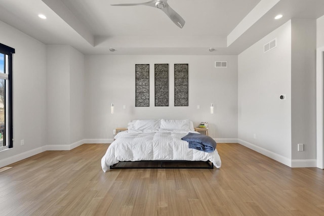 bedroom featuring visible vents, a raised ceiling, and light wood-style floors