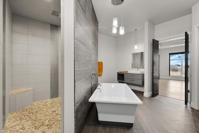 bathroom featuring vanity, wood finished floors, visible vents, baseboards, and a tile shower