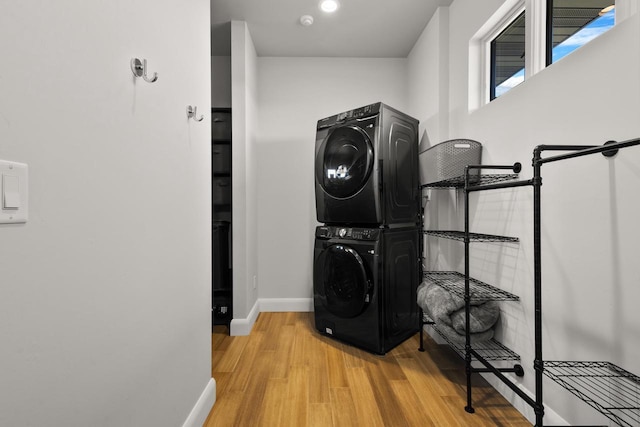 washroom with laundry area, wood finished floors, stacked washer and clothes dryer, and baseboards