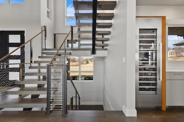 staircase with baseboards, wood finished floors, and a towering ceiling