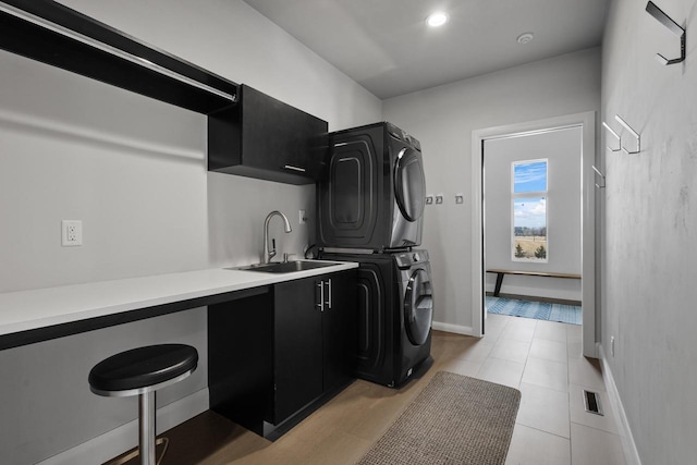 laundry room with stacked washer and dryer, a sink, recessed lighting, cabinet space, and baseboards