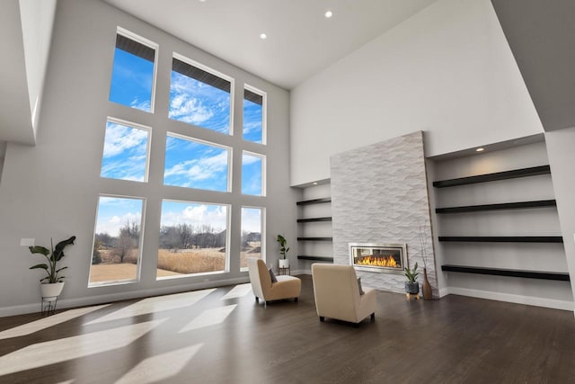 living room with built in shelves, a glass covered fireplace, wood finished floors, recessed lighting, and baseboards