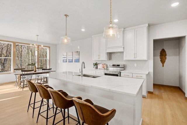 kitchen with backsplash, light wood-style flooring, electric range, white cabinetry, and a sink