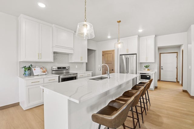 kitchen featuring white cabinetry, appliances with stainless steel finishes, a breakfast bar area, and a sink