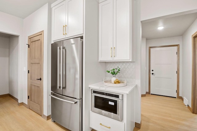 kitchen with white cabinetry, light countertops, backsplash, and stainless steel appliances