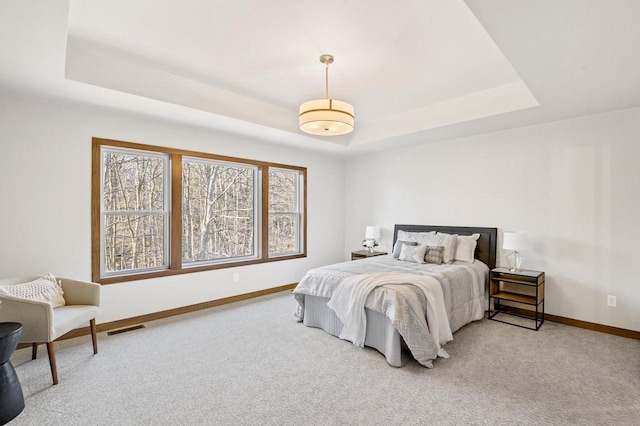 bedroom with a tray ceiling, baseboards, and visible vents