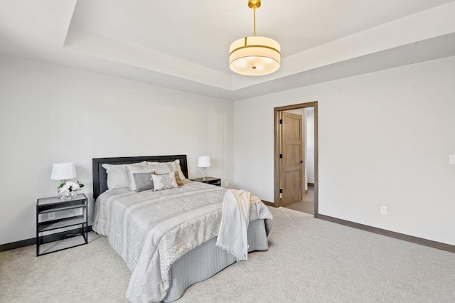 carpeted bedroom with baseboards and a raised ceiling