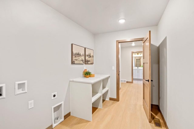 hall featuring light wood-style flooring, baseboards, and visible vents