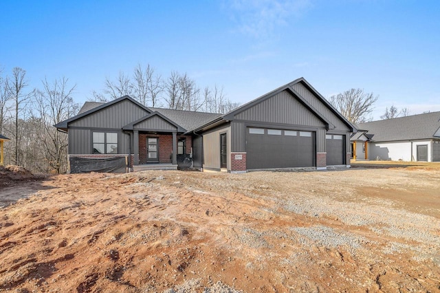 view of front of house with brick siding, board and batten siding, a garage, and dirt driveway