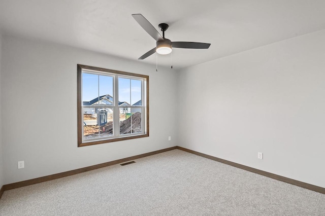 carpeted empty room featuring a ceiling fan, visible vents, and baseboards