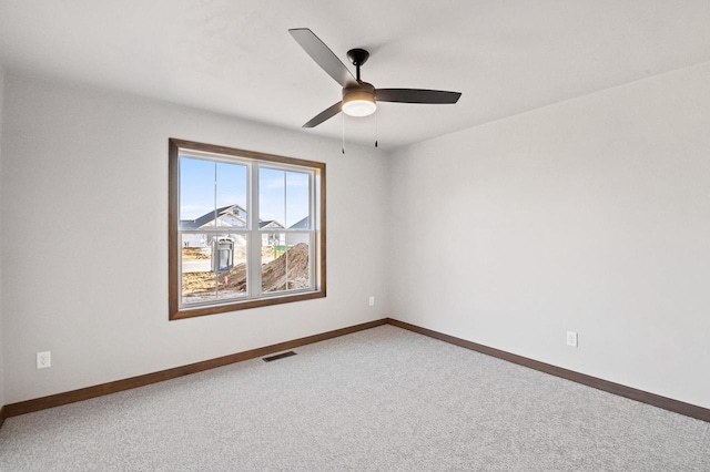 carpeted spare room featuring baseboards, visible vents, and ceiling fan