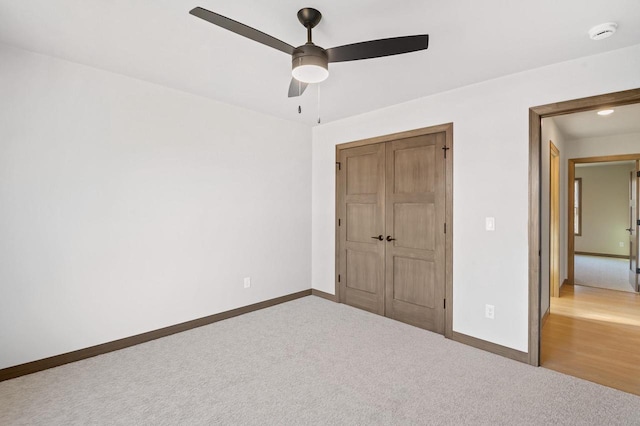 unfurnished bedroom with carpet flooring, baseboards, a closet, and ceiling fan