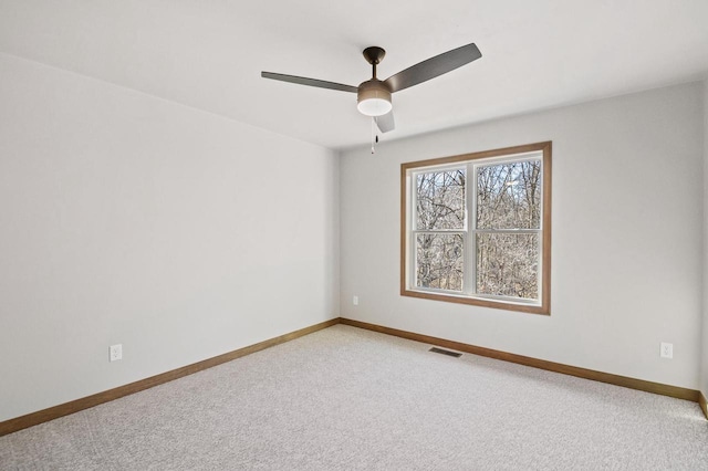 unfurnished room with visible vents, baseboards, light colored carpet, and ceiling fan