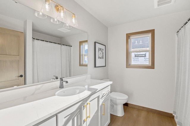 bathroom with vanity, wood finished floors, visible vents, baseboards, and toilet