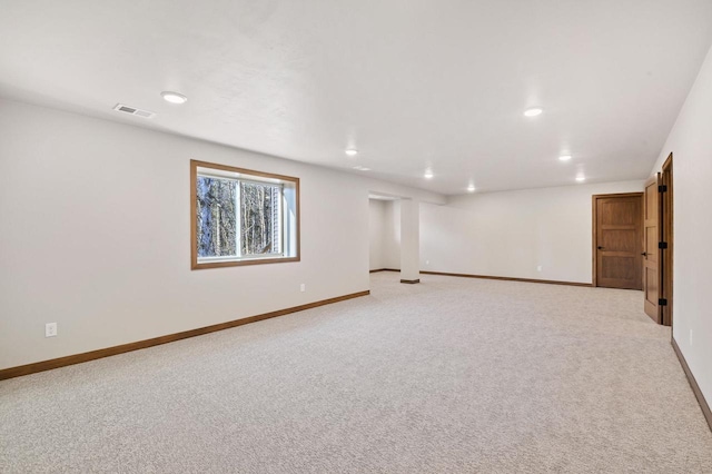 basement featuring visible vents, baseboards, and light colored carpet