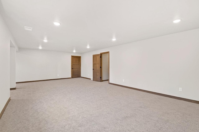 empty room featuring recessed lighting, light colored carpet, and baseboards