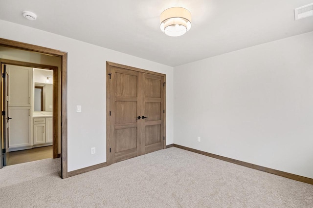 unfurnished bedroom with visible vents, baseboards, a closet, and carpet flooring