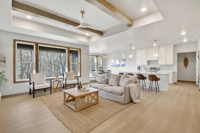 living area featuring baseboards, recessed lighting, ceiling fan, beamed ceiling, and light wood-type flooring